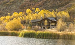 home exterior on a lake with yellow aspens around it