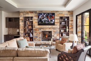 living room with flat screen on wall above stone fireplace