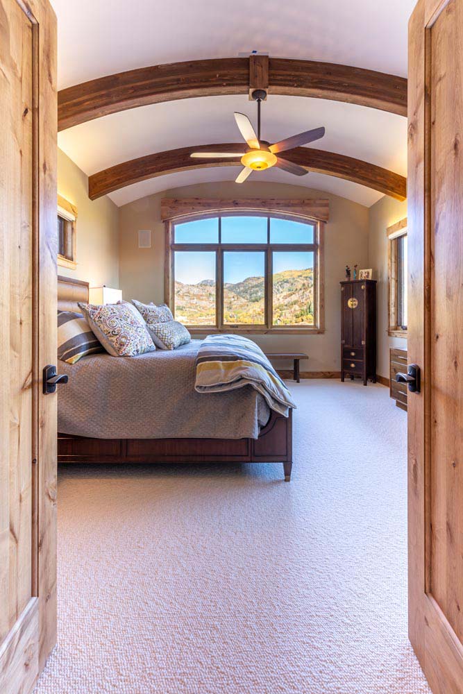 Open doors leading into bedroom with round ceiling and beams.