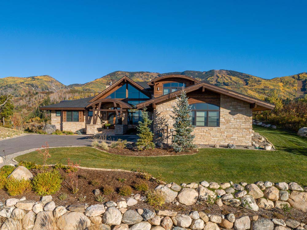 Trees and landscaping surround custom mountain home in front of Steamboat Resort.