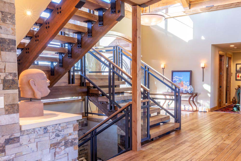 Open staircase with custom railings and wood beam steps with industrial metal.