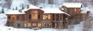 Large log style home on a snow covered hillside.