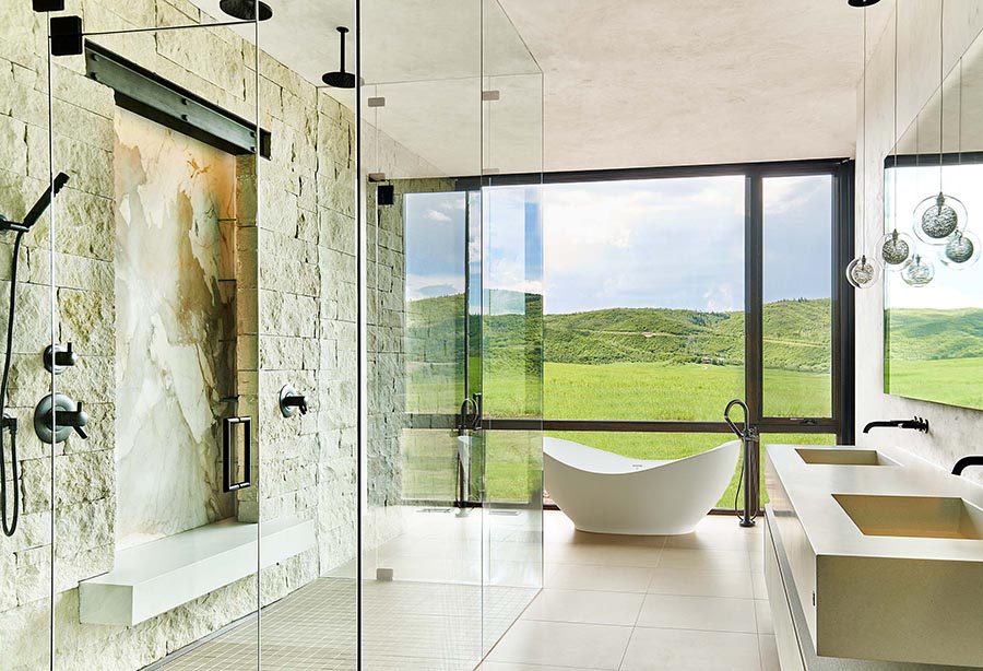 White modern bathroom with floor to ceiling glass shower and free standing tub.
