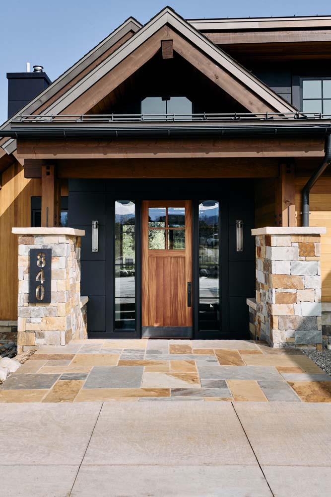 Outside entry with black walls, wood door and stone.