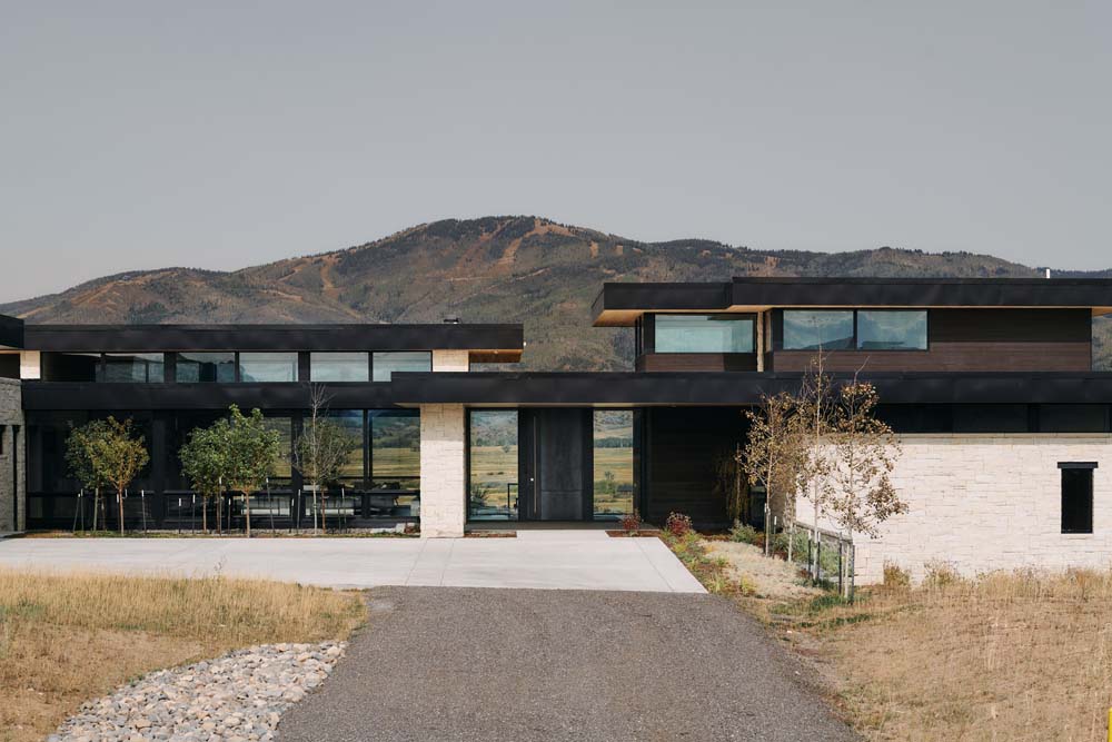 Driveway up to large modern home with mountains in the background